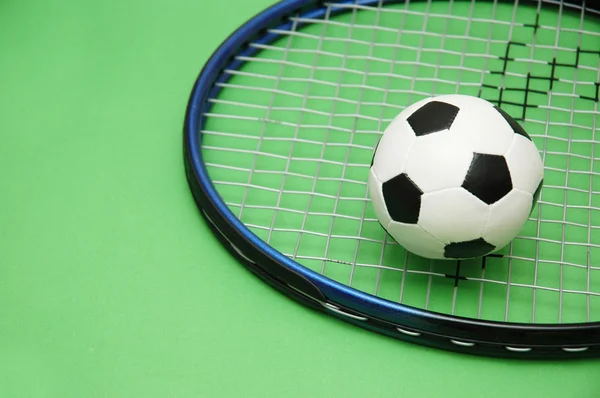 Futebol e raquete de tênis em fundo verde — Fotografia de Stock