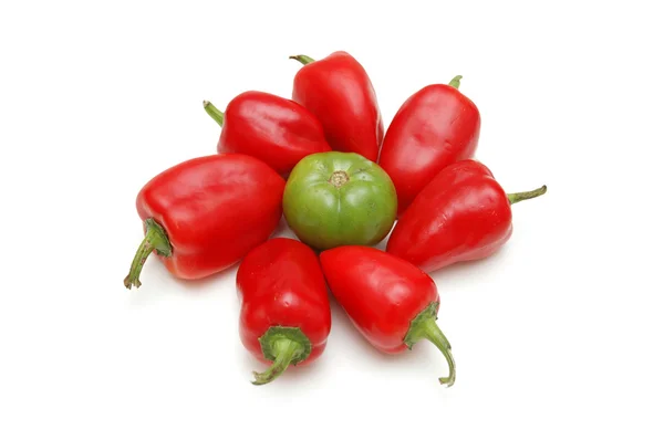 Rote Paprikaschoten um grüne Tomaten isoliert auf weißen angeordnet — Stockfoto