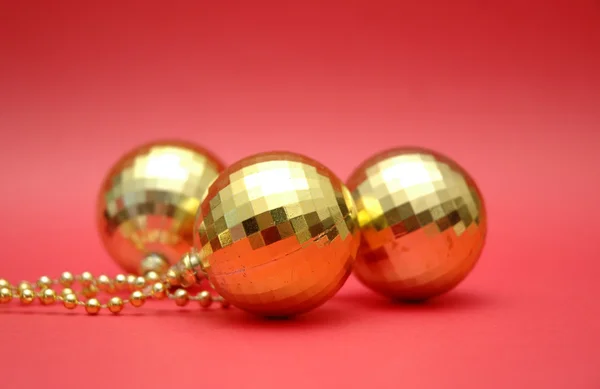 Três bolas douradas no fundo vermelho — Fotografia de Stock