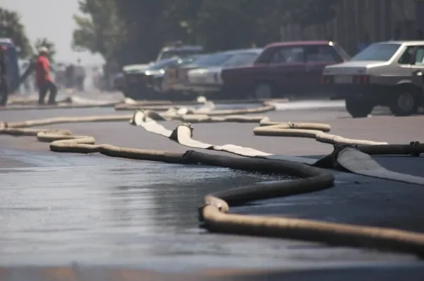 Fire hoses stretching across the street during fire in the city — Stock Photo, Image
