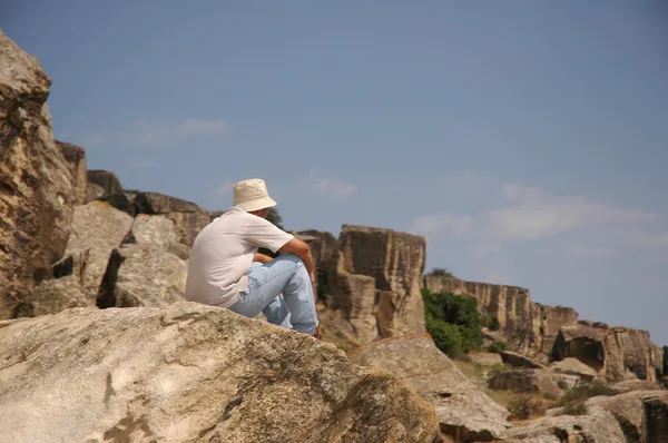 Homem sentado no topo da rocha — Fotografia de Stock