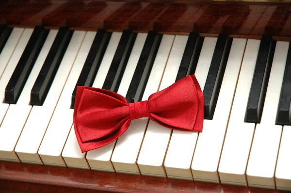 Laço vermelho em teclas de piano — Fotografia de Stock