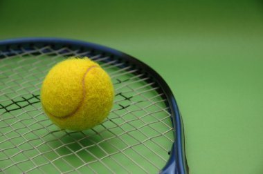 Tennis ball and racket on green background clipart