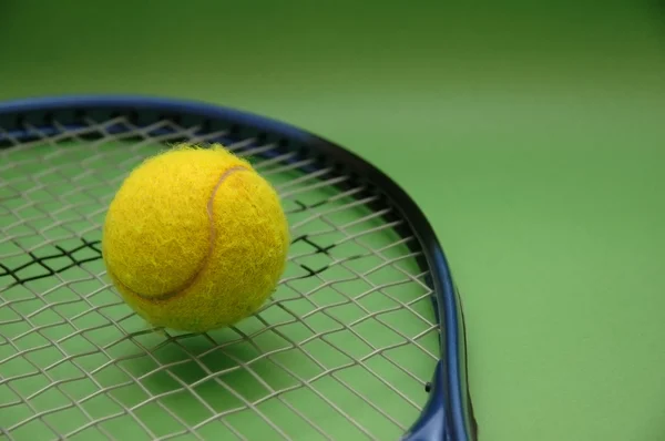 Pelota de tenis y raqueta sobre fondo verde —  Fotos de Stock