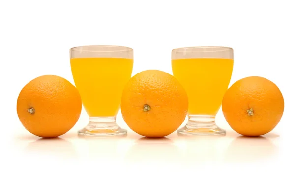 Апельсины и стаканы апельсинового сока — стоковое фото