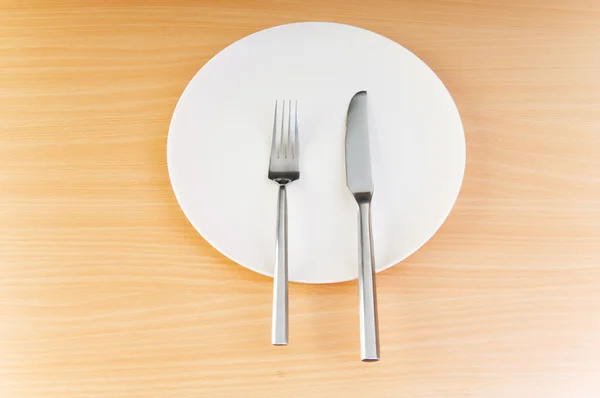 Teller mit Utensilien auf Holztisch — Stockfoto
