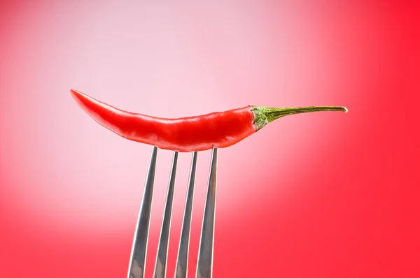 Peppar på gaffeln mot färg bakgrund — Stockfoto