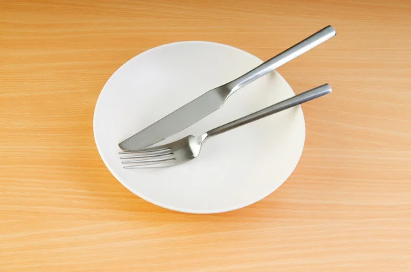 Plate with utensils on wooden table — Stock Photo, Image