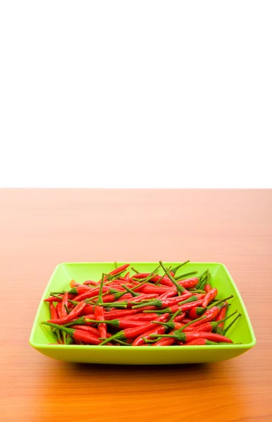 Peperoni caldi nel piatto sul tavolo di legno — Foto Stock