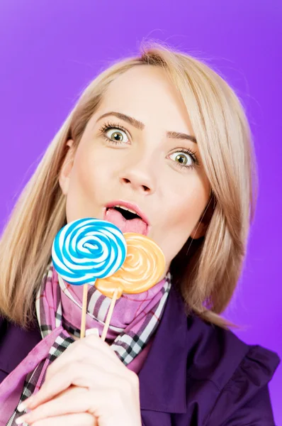 Meisje met lolly tegen kleurrijke achtergrond — Stockfoto