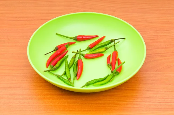 Hot peppers in the plate on wooden table — Stock Photo, Image