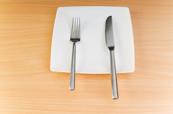 Piatto con utensili su tavolo in legno — Foto Stock
