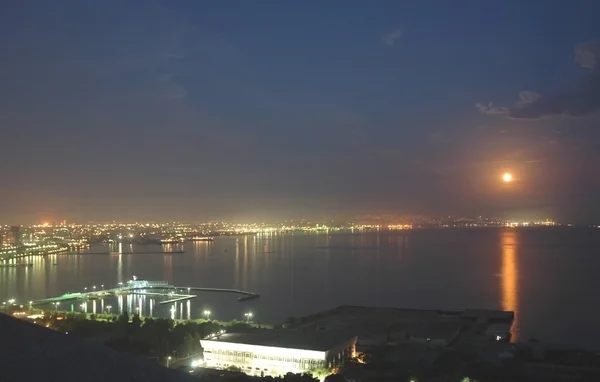 Bakoe stad bij nacht en reflectie van de maan in het water — Stockfoto