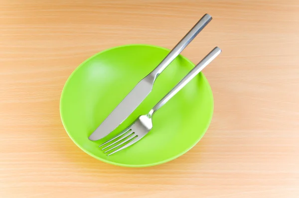 Plate with utensils on wooden table — Stock Photo, Image