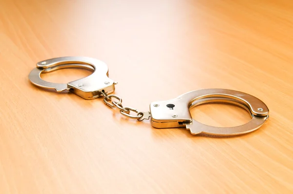 Metal handcuffs on the wooden background — Stock Photo, Image