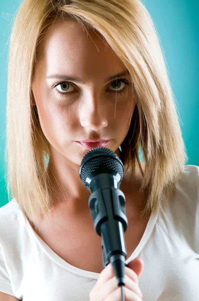 Menina cantando com microfone contra fundo gradiente — Fotografia de Stock