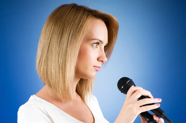 Jentesang med mikrofon mot helningsbakgrunn – stockfoto