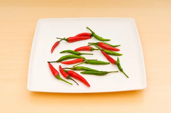 Paprika im Teller auf Holztisch — Stockfoto