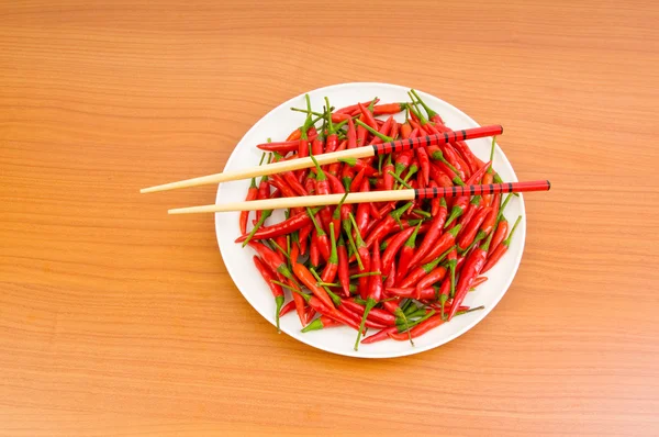 Hot peppers with chopsticks and plate — Stock Photo, Image