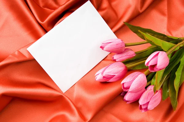 Envelop en bloemen op de satijnen ondergrond — Stockfoto