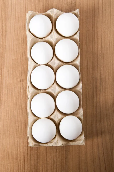 Muitos ovos brancos na mesa de madeira — Fotografia de Stock