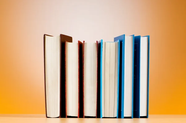 Empilhamento de livros de texto contra fundo gradiente — Fotografia de Stock