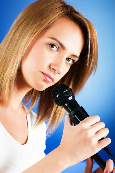 Girl singing with microphone against gradient background — Stock Photo, Image