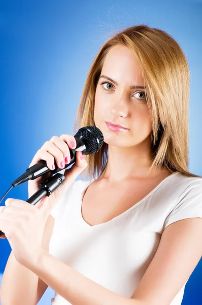 Девушка поет с микрофоном на градиентном фоне — стоковое фото