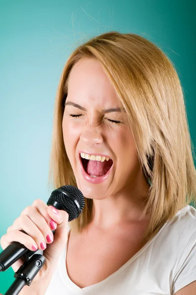 Ragazza che canta con microfono su sfondo sfumato — Foto Stock