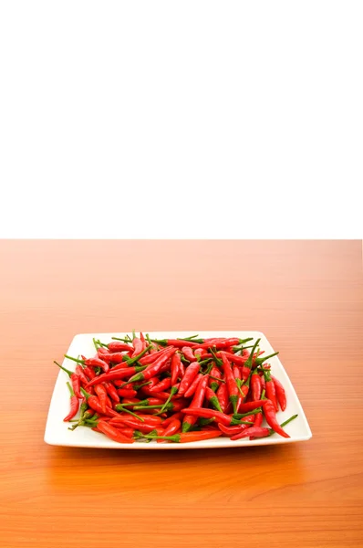 Peperoni caldi nel piatto sul tavolo di legno — Foto Stock