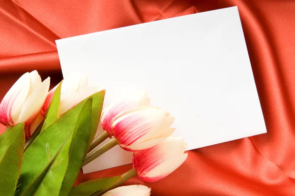 サテンの背景の封筒と花 — ストック写真