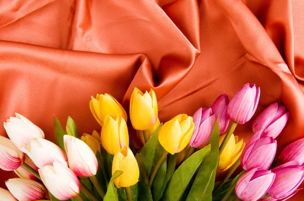 Many flowers on the red satin background — Stock Photo, Image
