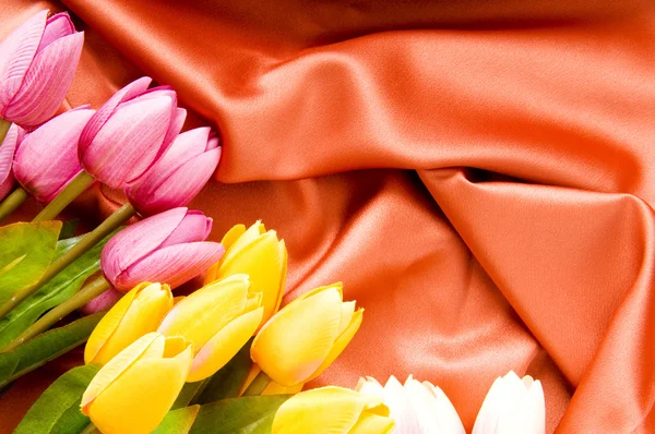 Mnoho květin na červeném saténovém pozadí — Stock fotografie