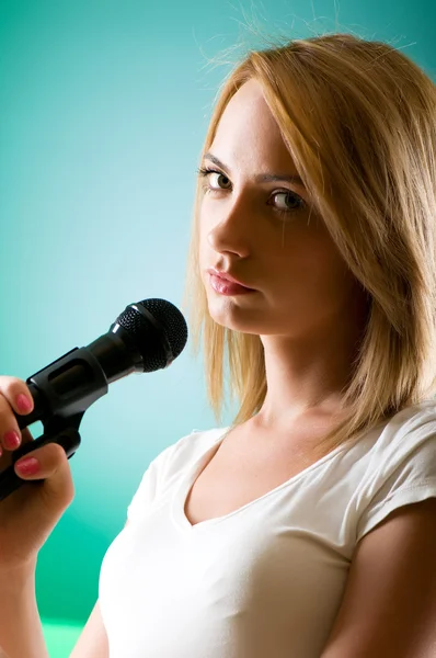 Дівчина співає з мікрофоном на градієнтному фоні — стокове фото