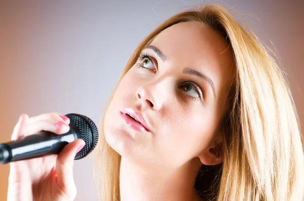 Mikrofon degrade arka plan ile şarkı söyleyen kız — Stok fotoğraf