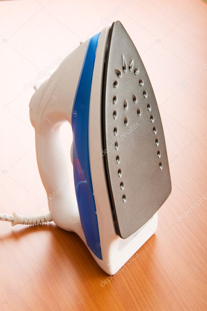 Modern electric iron on the wooden background