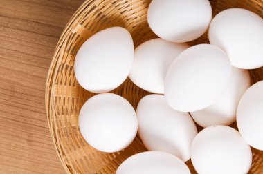 ahşap masa üzerinde birçok beyaz yumurta