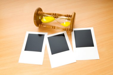 Blank instant photos and hour glass on the wooden table clipart