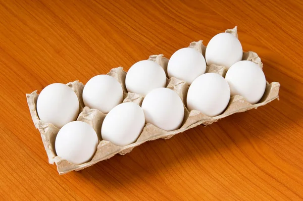 A fából készült asztal sok fehér tojás — Stock Fotó