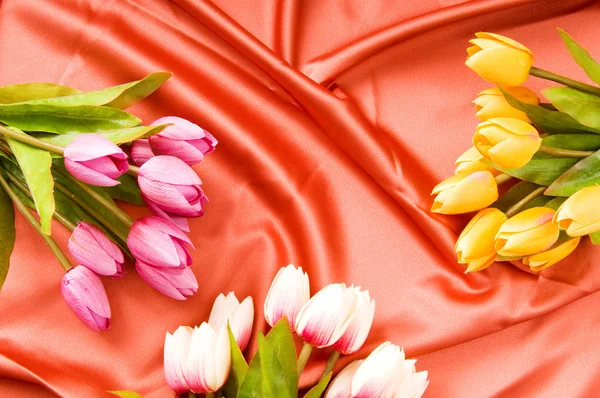 Molti fiori sullo sfondo di raso rosso — Foto Stock