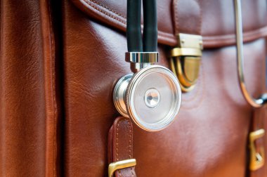 Doctor's case with stethoscope against wooden background clipart