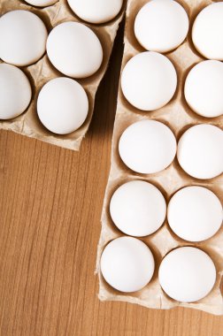 ahşap masa üzerinde birçok beyaz yumurta