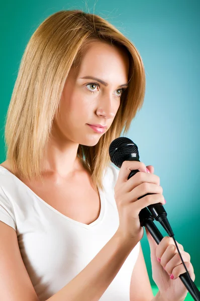 Девушка поет с микрофоном на градиентном фоне — стоковое фото