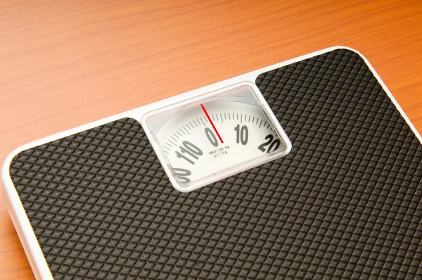 Dieting concept with scales on the wooden floor — Stock Photo, Image