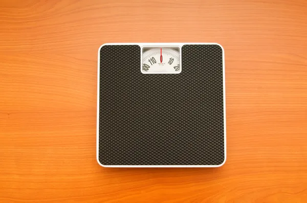 Conceito de dieta com balanças no chão de madeira — Fotografia de Stock