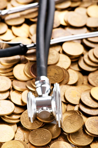 Conceito de cuidados de saúde caros com moedas e estetoscópio — Fotografia de Stock