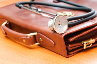 Doctor's case with stethoscope against wooden background clipart
