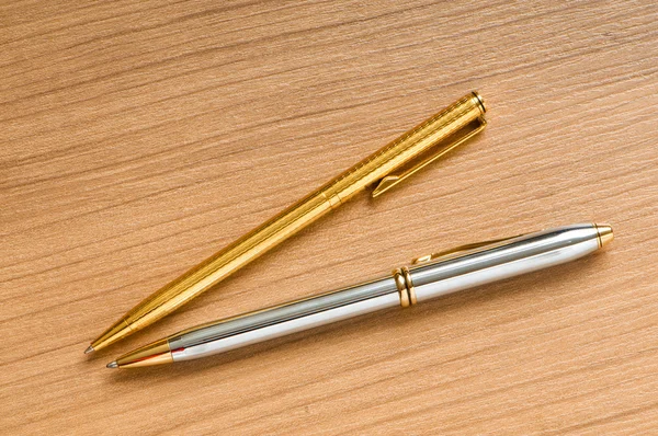 Написание серебряной ручки на деревянном фоне — стоковое фото
