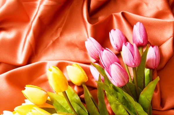 Veel bloemen op de rode satijnen achtergrond — Stockfoto