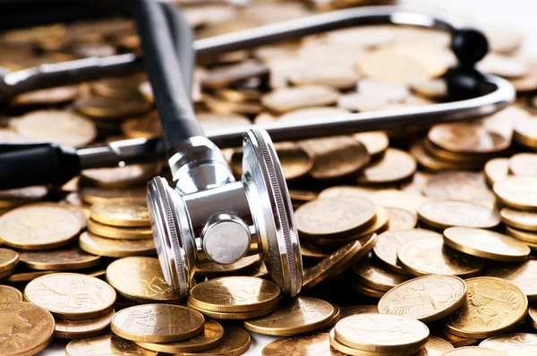 Concetto di assistenza sanitaria costosa con monete e stetoscopio — Foto Stock